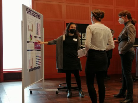 Drei Personen stehen vor einem Plakat und diskutieren
