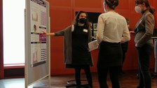 Drei Personen stehen vor einem Plakat und diskutieren