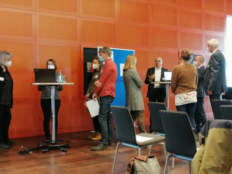 Personen stehen an Stehtischen und diskutieren