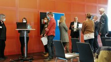 Personen stehen an Stehtischen und diskutieren