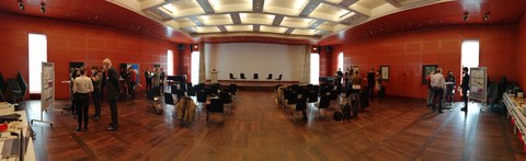 ein Panaromabild über den gesamten Saal. Personen stehen an Stehtischen und diskutieren.