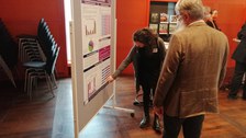 Eine Frau zeigt einem Mann etwas auf einem Poster.