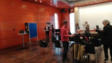Personen stehen verstreut im Raum und unterhalten sich