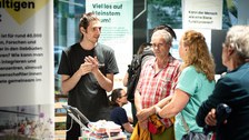 Foto von Besuchenden im Gespräch mit einem Wissenschaftler im COSMO Wissenschaftsforum