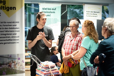 Foto von Besuchenden im Gespräch mit einem Wissenschaftler im COSMO Wissenschaftsforum