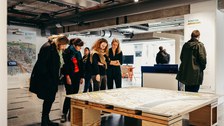 Foto von einer Gruppe von Personen, die im COSMO Wissenschaftsforum ein Ausstellungsobjekt betrachten