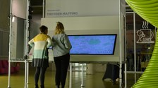 Zwei Personen stehen vor einem sehr großen interaktiven Display zum Thema Dresden Mapping. 