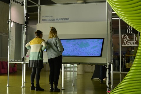 Zwei Personen stehen vor einem sehr großen interaktiven Display zum Thema Dresden Mapping. 
