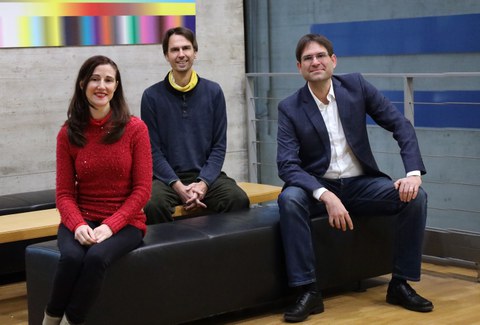drei Menschen sitzen zusammen und lächeln