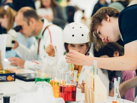 A photo of a person showing a child a test tube with colored water.