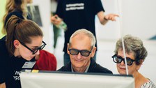 A photo of three people who are looking at a screen while wearing special glasses.