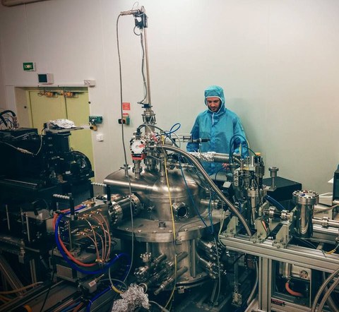 A man in protective clothing stands behind a complex machine