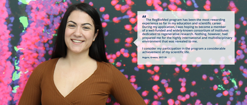 A portrait photo with text. A smiling person on a black background with clustered specks in pink, purple, and green. On the right side of the photo, there is a white rectangle with a big quotation mark and text: ”The RegBioMed program has been the most rewarding experience so far in my education and scientific career. During my application, I was hoping to become a member of a well-funded and widely-known consortium of institutes dedicated to regenerative research. Nothing, however, had prepared me for the highly international and multidisciplinary environment that was revealed to me. I consider my participation in the program a considerable achievement of my scientific life. Argyro, Greece, 2017-19.”