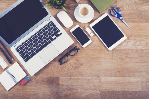 Laptop, Handy und weitere Arbeitsmittel auf Schreibtisch