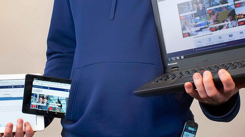 Person hält verschiedene mobile Endgeräte mit aufgerufener TUD-Webseite in den Händen