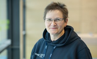 Foto: Frau mit kurzen grau-schwarzen Haaren, im dunkelblauen Kapuzenpullover mit DHSZ-Logo
