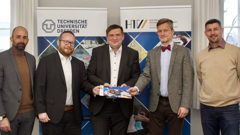 Foto fünf Menschen in festlicher Kleidung, der in der Mitte hält eine bunte Mappe