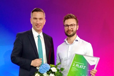 zwei Männer, der Mann links hält eine Urkunde