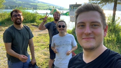 vier Männer, im Hintergrund ein See