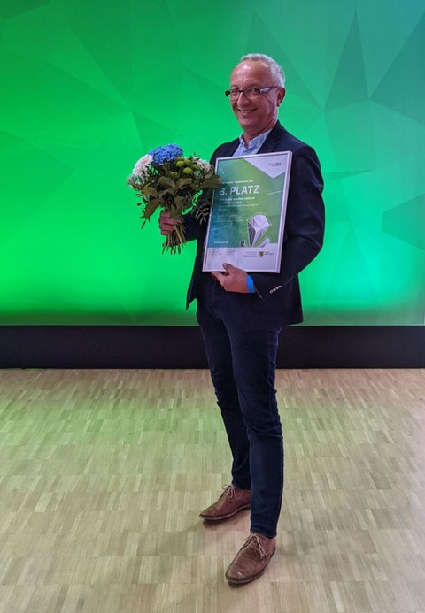 Mann mit Urkunde und Blumenstrauß