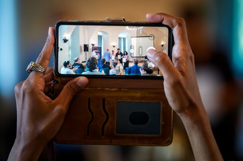 Teilnehmerin fotografiert präsentierendes Team mit ihrem Handy