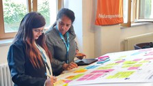zwei Teilnehmende arbeiten zusammen an ihrem Präsentationsboard