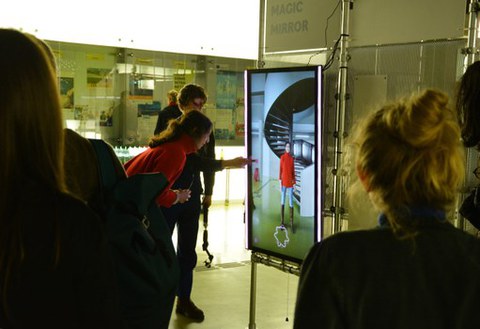 Blick in die Ausstellung DataSpaces, wo zwei Personen vor einem Bildschirm stehen und mit KI Fotos machen
