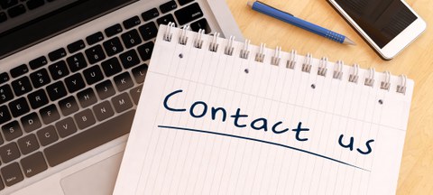 Contact us - handgeschriebener Text in einem Notizbuch auf einem Schreibtisch