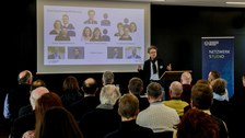 Impression aus der Veranstaltung. Vortragender vor Leinwand mit Präsentation zum Thema Farbe