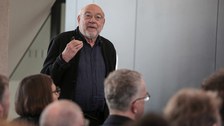 Impression aus der Veranstaltung. Vortragender vor Leinwand mit Präsentation zum Thema Farbe