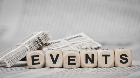 Holzwürfel mit jeweils einem Buchstaben, zusammen: "EVENTS". Würfel liegen auf Berliner Zeitung.