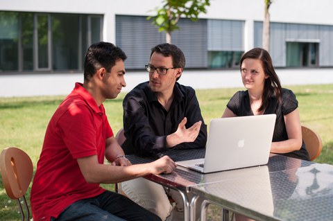 Drei Wissenschaftler:innen diskutieren vor einem Laptop