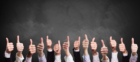 thumbs up in front of a blackboard