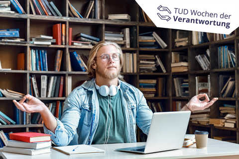 Junger blonder Mann mit brille sitzt in Meditationsposition vor seinem Laptop in der Bibliothek