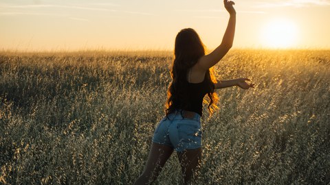 A woman in a field at sunset 