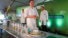 Studierende in weißen Kitteln präsentieren ein Chemieexperiment zum Mitmachen bei den Zukunfstagen Hirschfelde
