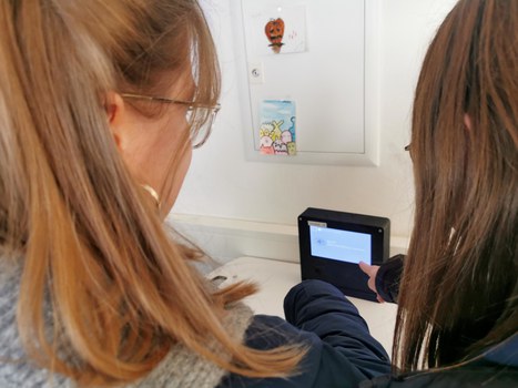 Zwei Studentinnen zeigen auf ein Terminal auf einem Laptopschrank.