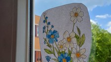 Durch ein Klassenraumfenster sieht man auf den Schulhof der Pestalozzi-Oberschule Löbau. Am Fenster klebt ein handgemaltes Blumenbild.