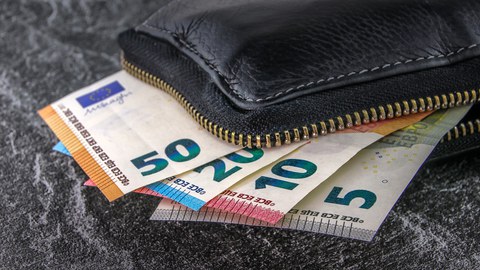 Aus einer Geldbörse schauen Geldscheine heraus. Es sind 5 Euro, 10 Euro, 20 Euro und 50 Euro.