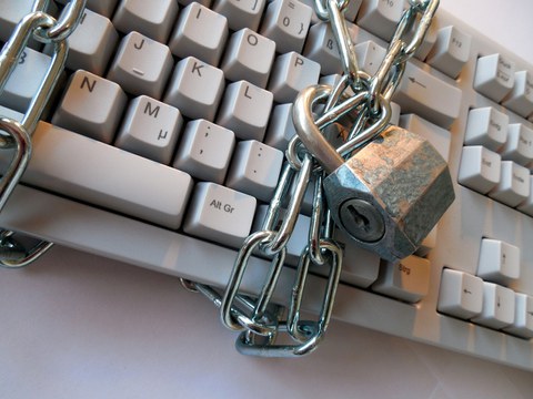 Foto: Computertastatur die mit einer Eisenkette umwickelt und einem Schloss verschlossen ist.