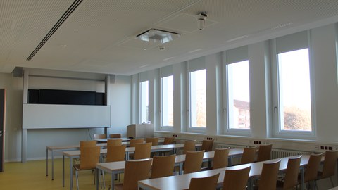 Raum mit Stuhlreihen und einer Tafel
