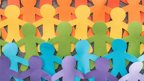 Bild zeigt sechs Reihen aus bunten Papierschnittfiguren auf grauem Hintergrund in LGBT Regenbogenfarben.