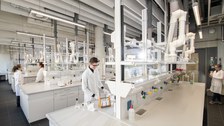 Es stehe mehrere Studierende an Labor Tischen im Labor.