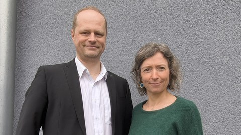 Drik Wohlraabe und Nadine Matthes stehen nebeneinander und schauen freundlich in die Kamera.