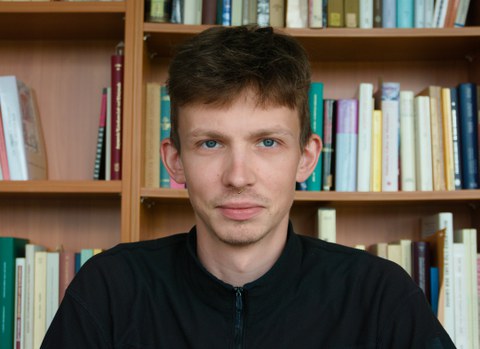 Ein lächelnder Mann vor einem Bücherregal
