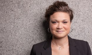 Eine lächelnde Frau vor einer grauen Wand