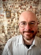 Ein lächelnder Mann vor einer historischen Landkarte