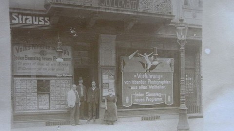 Volks-Kinematograph mit Schaufenster, Werbeflächen und Menschen vor dem Eingang