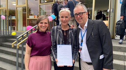 Photo of Angela Dressen with her certificate of appointment, flanked by Jurgen Müller and Kerstin Schankweiler