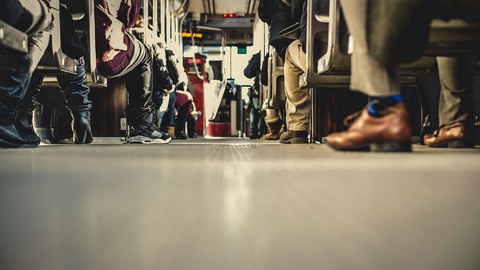 Foto vom Boden aus von einem Bus, in dem rechts und links viele Fahrgäste sitzen